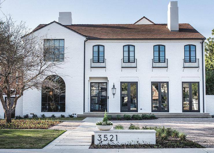 Gorgeous home features a white painted brick exterior accented with balconies over steel framed doors located on the first floor.