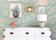gallery wall on green pattern wallpaper white chest dresser flamingo head hanging on wall