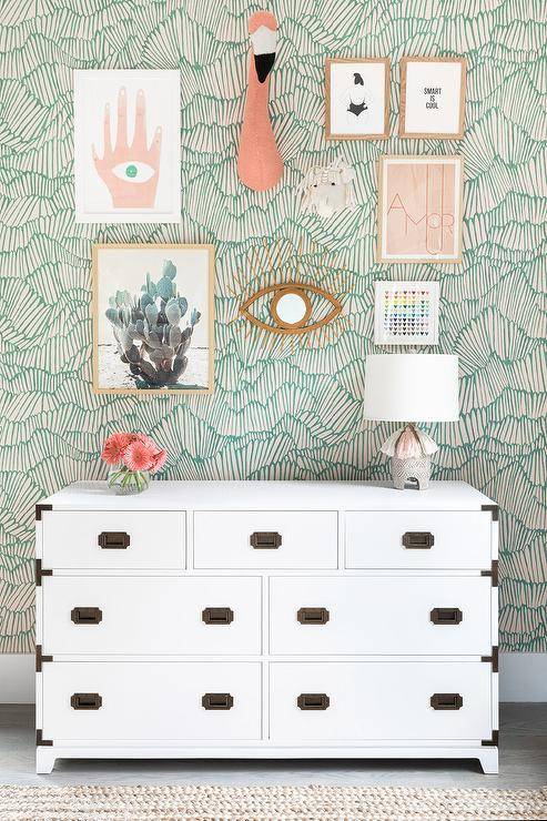 gallery wall on green pattern wallpaper white chest dresser flamingo head hanging on wall