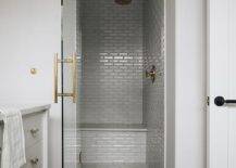 grey subway tile walk in shower with gold faucets glass door with gold hardware