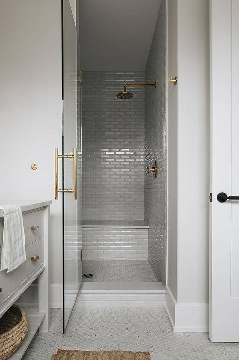 grey subway tile walk in shower with gold faucets glass door with gold hardware