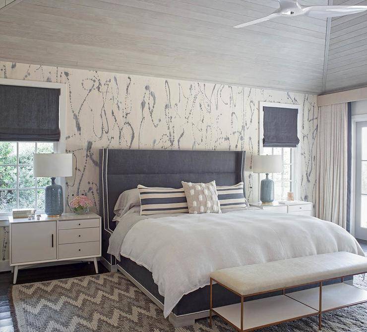 large primary bedroom dark blue headboard pattern wallpaper white bedding nightstands table lamps