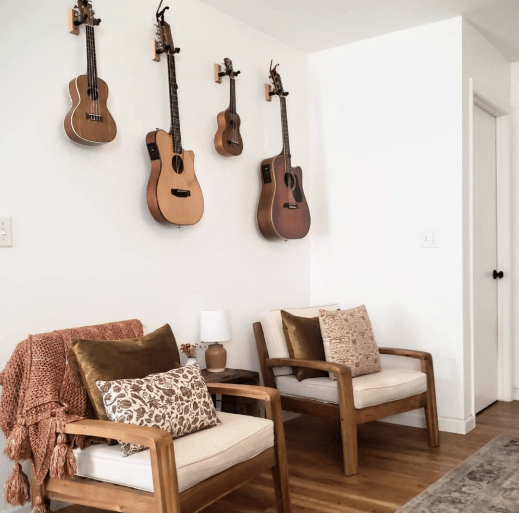 hanging guitars in room white wall with two sitting chairs and decorative pillows