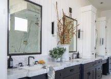 Black and white master bathroom features black vanity mirrors hung from a vertical shiplap wall over a black dual washstand donning matte black hardware and a white and gray marble countertop finished with matte black faucets.
