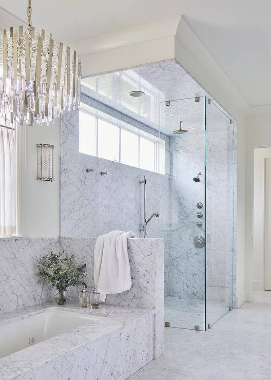 large marble walk in shower with marble tub crystal chandelier glass door