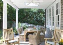 Covered patio features teak rocking chairs on slate pavers with round side tables.