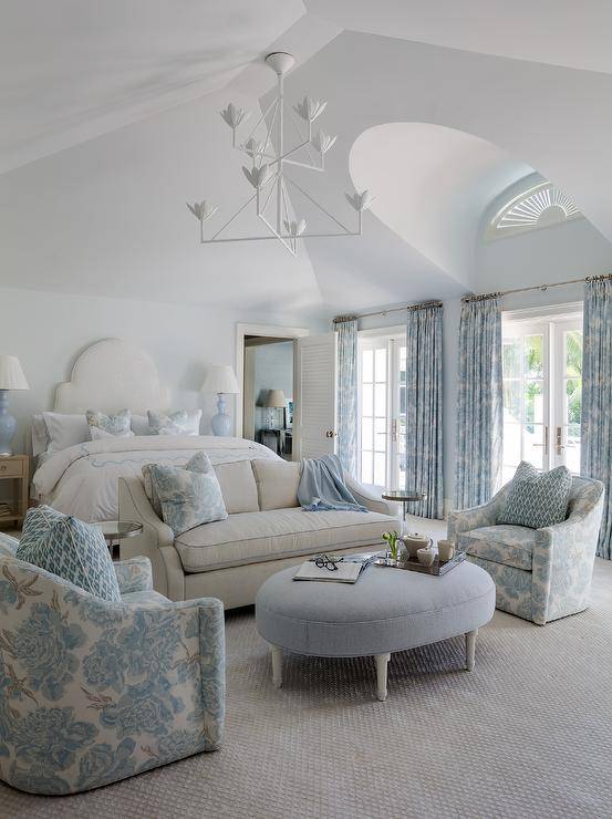 gray bedroom boasts a sitting area styled with a light gray sofa lined with blue piping and topped with a blue floral pillow.