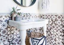 mixed tile patterns in half bathroom on wall black round mirror white pedestal sink