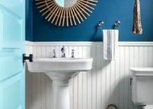 half blue half white board and batten wall bathroom pedestal sink white with sunburst rattan mirror hanging plant