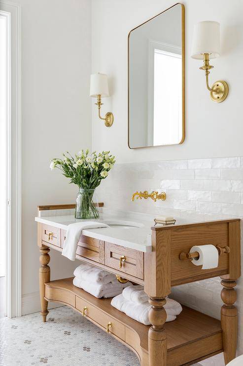brown wood open bottom bathroom vanity with gold faucet sink toilet paper holder gold frame mirror wall sconces