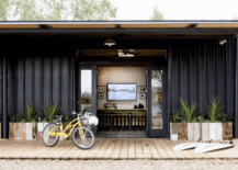 black siding house with open doors and bike on front porch