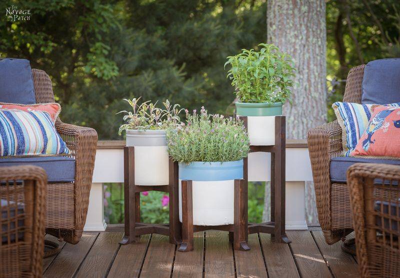 pottery barn inspired diy outdoor plant stands stained dark walnut wood painted crocks with herbs in them next to two wicker patio chairs