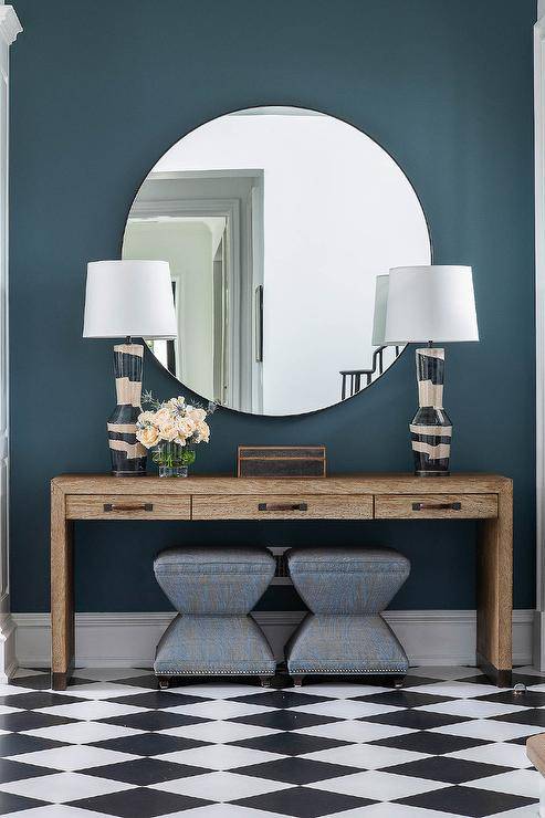 console table with a contemporary finish flat large round mirror with no frame and two table lamps black and white checker floor