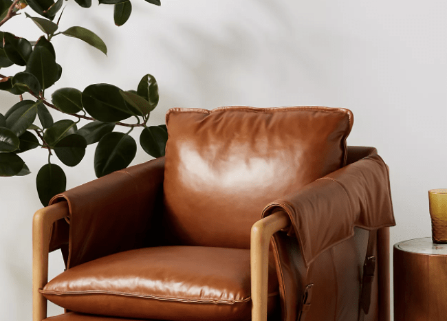 brown leather arm chair on mustard yellow carpet with tree greenery in background