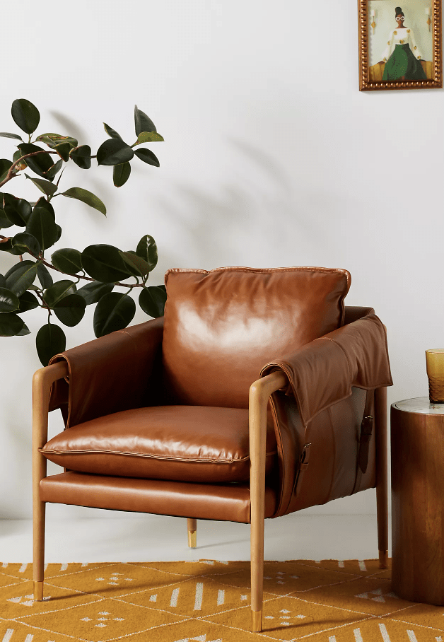 brown leather arm chair on mustard yellow carpet with tree greenery in background
