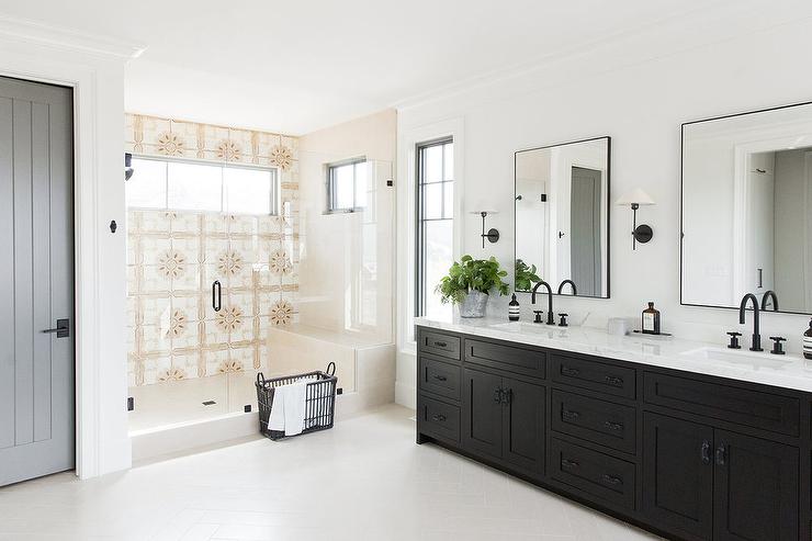 Black dual washstand with black matte faucets and slim black metal framed mirrors flanked by black and white sconces in a transitional bathroom with a glass enclosed walk-in shower.