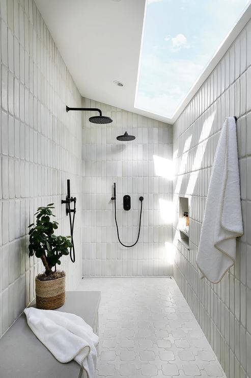 sloped ceiling walk in shower with skylight window black faucets hanging white towel