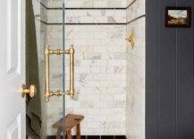 small walk in shower with marble subway tiles glass door with gold hardware black floor tile