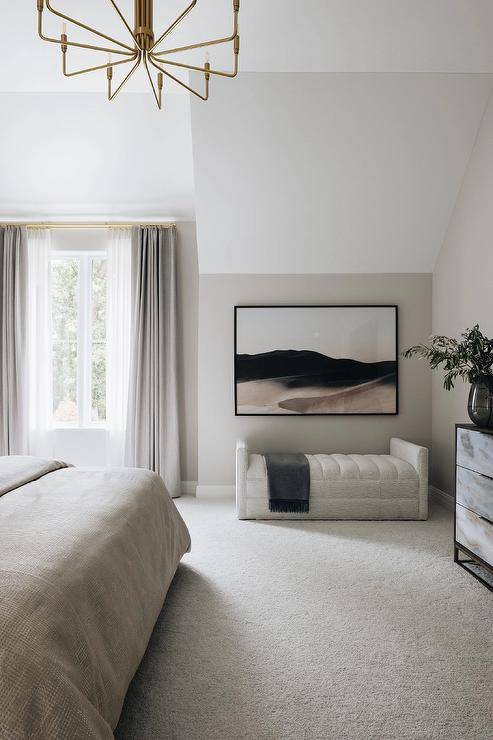 smaller black frame abstract art in bedroom with tufted bench and gold chandelier