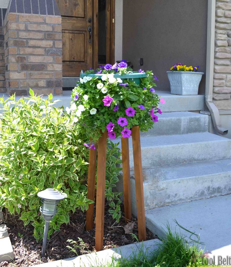 tall wooden leg plant stand in front garden next to concrete steps