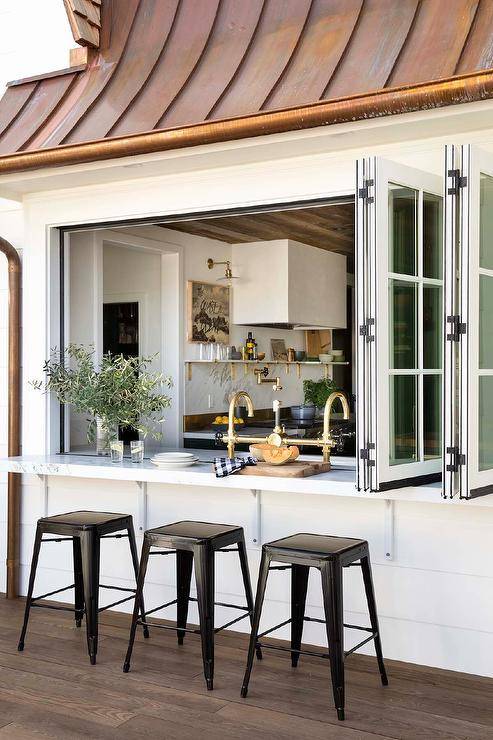 A folding kitchen pass-through windows open to a patio bar seating four black Tolix stools.
