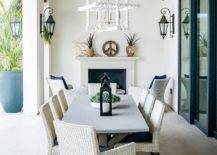 Light gray wicker dining chairs designed around a wood and concrete trestle dining table in an outdoor covered patio.