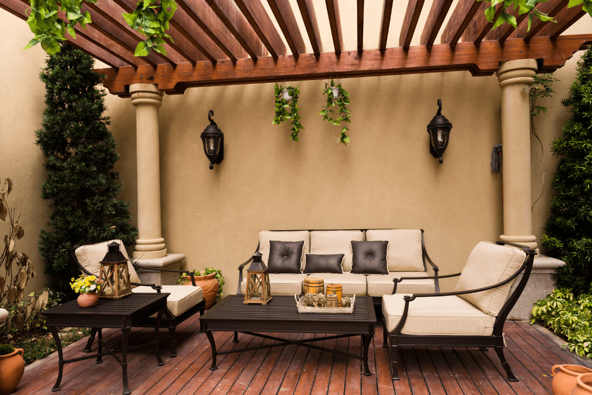 urban patio with black outdoor lighting wall sconce pergola white cream patio furniture cushions and black wrought iron patio furniture