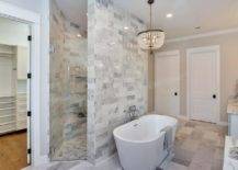 walk in shower tiled wall behind oval tub crystal chandelier
