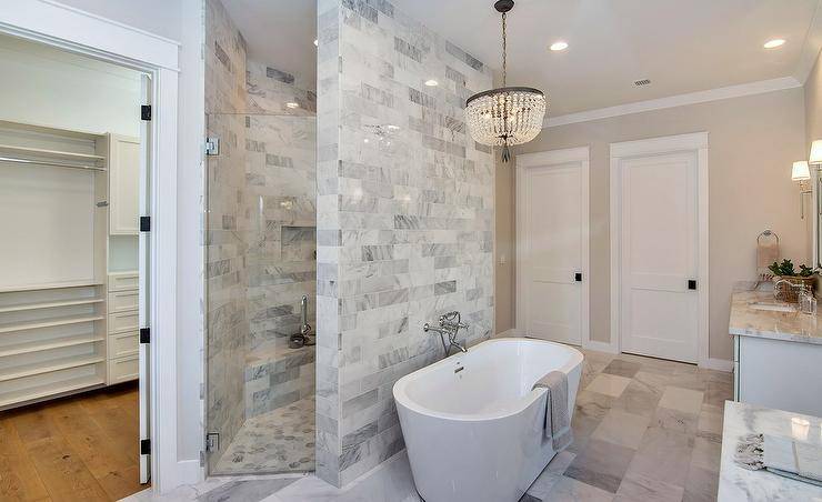 walk in shower tiled wall behind oval tub crystal chandelier