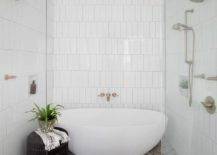 walk in shower with white tiles pattern floor tile glass door and oval tub inside