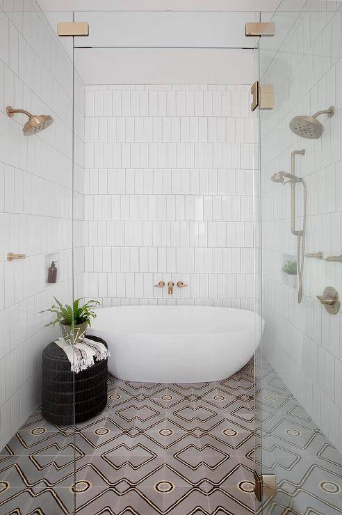 walk in shower with white tiles pattern floor tile glass door and oval tub inside