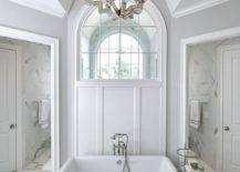 arch window walk in shower with large chandelier and tub in front