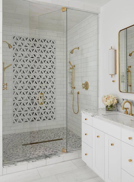 walk in shower with mosaic tile design art piece in middle gold shower kit white vanity with gold hardware wall light sconce glass doors