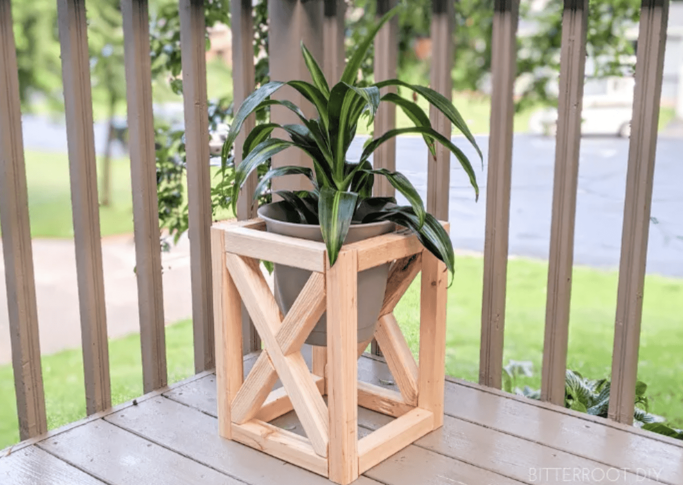 x frame wood outdoor plant stand with potted plant inside on porch