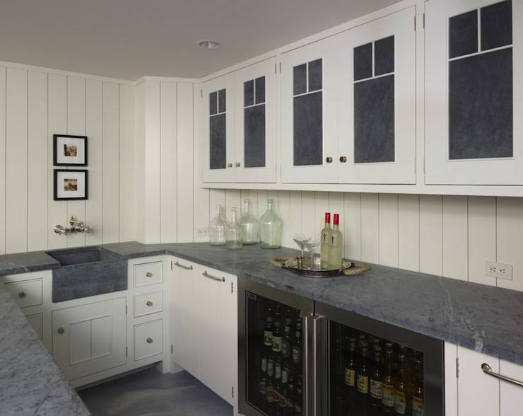 Basement wet bar with tongue and groove walls and white cabinets with concrete panel doors. White paneled kitchen cabinets with concrete countertops and concrete sink with polished nickel wall-mount faucet kit. Glass-front mini-fridges, white wood paneled dishwasher and recycled glass vases.