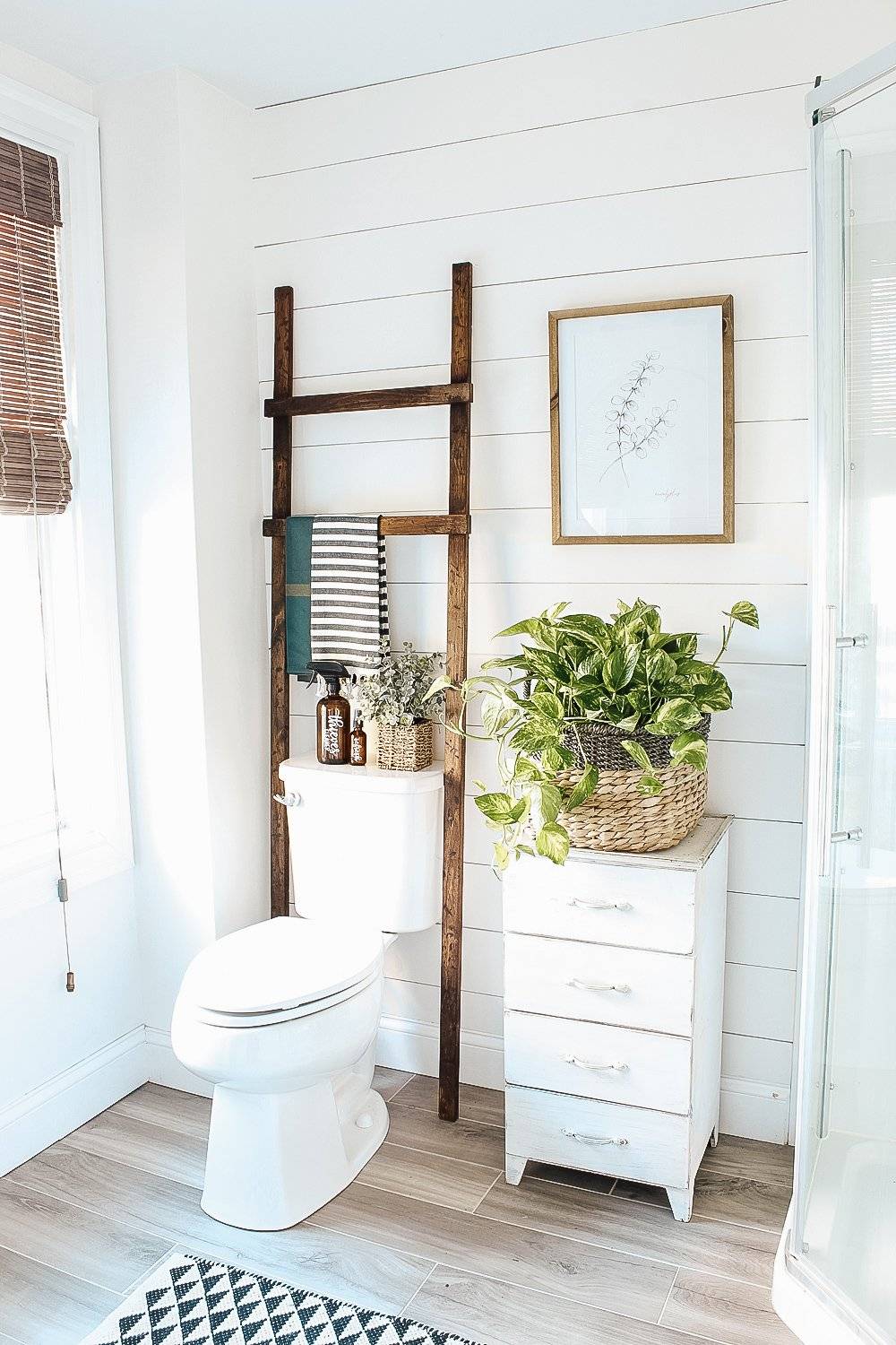 white shiplap wall bathroom ladder over toilet white four drawer shelf with potted plant