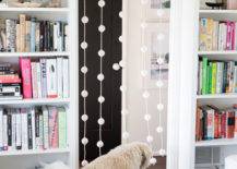 large beaded curtain dog walking through bookshelf on either side