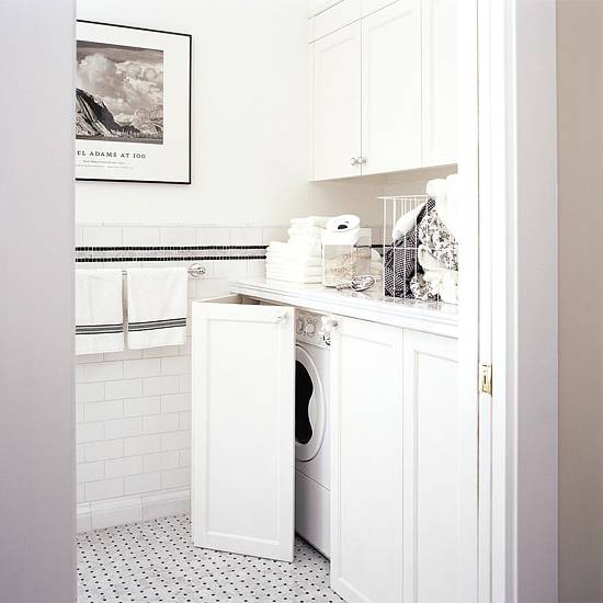 Laundry room with hidden washer and dryer, Front load washer and dryer hidden behind folding shaker cabinets doors. Laundry room with marble countertops, subway tile backsplash and marble basketweave tiles floor.