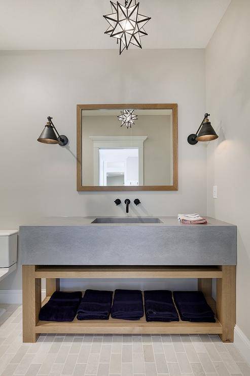 Amazing bathroom features a Moravian Star pendant suspended over a square wood mirror and wood washstand with a thick concrete sink.