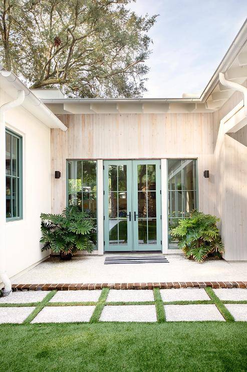 Patio features concrete pavers with grass trim and green blue doors.