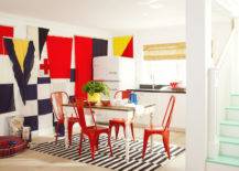 Burnham Design - Fabulous basement features a wall covered in flags beside kitchenette filled with Big Chill Refrigerator beside white cabinets topped with black countertop framing sink under window dressed in bamboo roller shades. A farmhouse dining table is lined with red metal dining chairs atop a World Market Black and White Striped Dhurrie Rug.