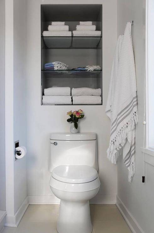 bathroom with white toilet built in shelves over toilet with white towels turkish towels hanging on wall