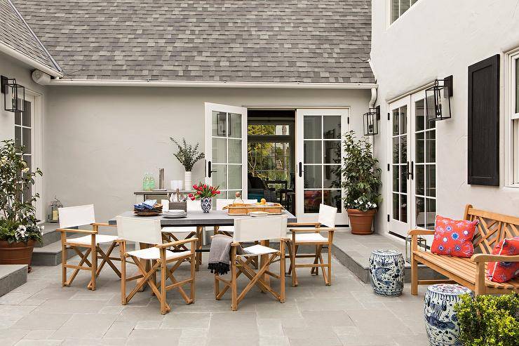 Ivory directors chairs sit on slate pavers around a concrete top patio dining table.