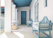 Cottage covered patio features a blue wooden bench under a blue plank ceiling matching window frames and doors.