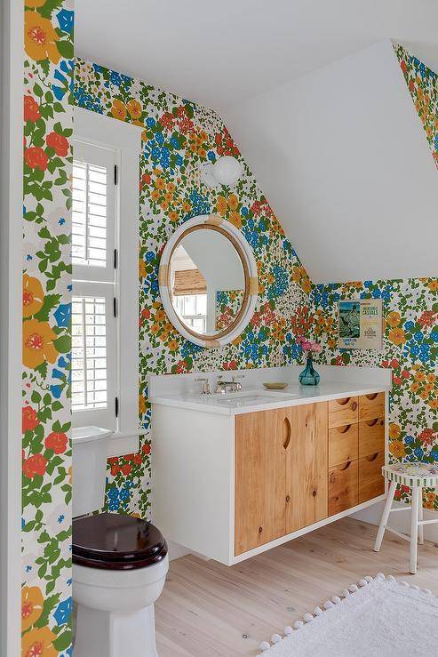 Bathroom features a Serena and Lily Montara mirror mounted on colorful floral wallpaper over a reclaimed wood floating washstand.