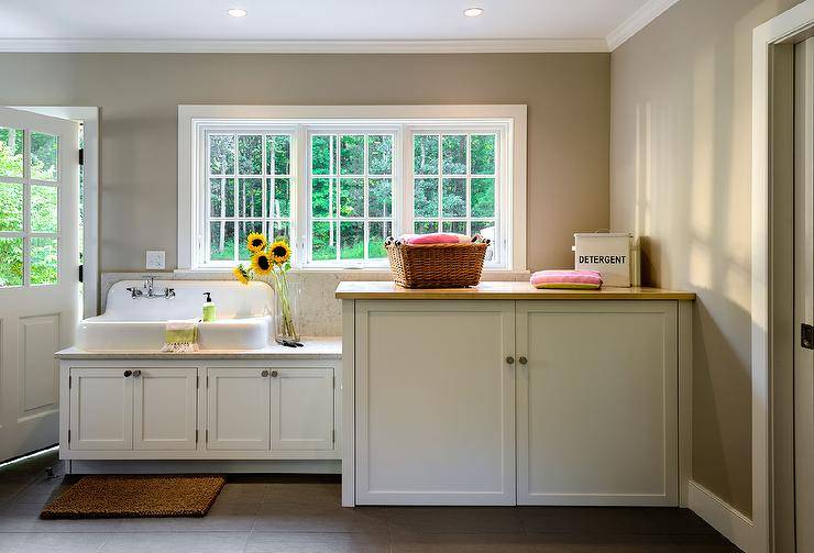 cottage laundry room features a vintage white porcelain sink next to a cabinet concealing a washer and dryer placed under windows.