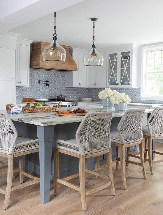 Vintage rope and glass lanterns light a blue kitchen island boasting a gray marble countertop and paired with BLU Home Loom Dining Chairs.
