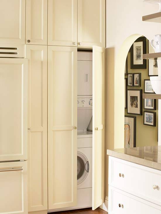 Back wall of kitchen cabinetry painted Grant Beige by Benjamin Moore. The back cabinetry includes a wood paneled refrigerator and a stackable washer and dryer hidden behind cabinet doors! The remainder of the kitchen cabinetry is painted Benjamin Moore's Decorator White and features Limestone counters.