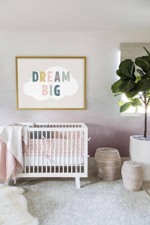 Nursery features Dream Big art on a pink ombre accent wall over a white Oeuf Sparrow crib and woven baskets on a light gray rug.