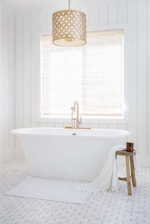 Gold lattice drum pendant above a vintage oval tub fitted with a polished nickel gooseneck faucet on a white and gray marble floor.